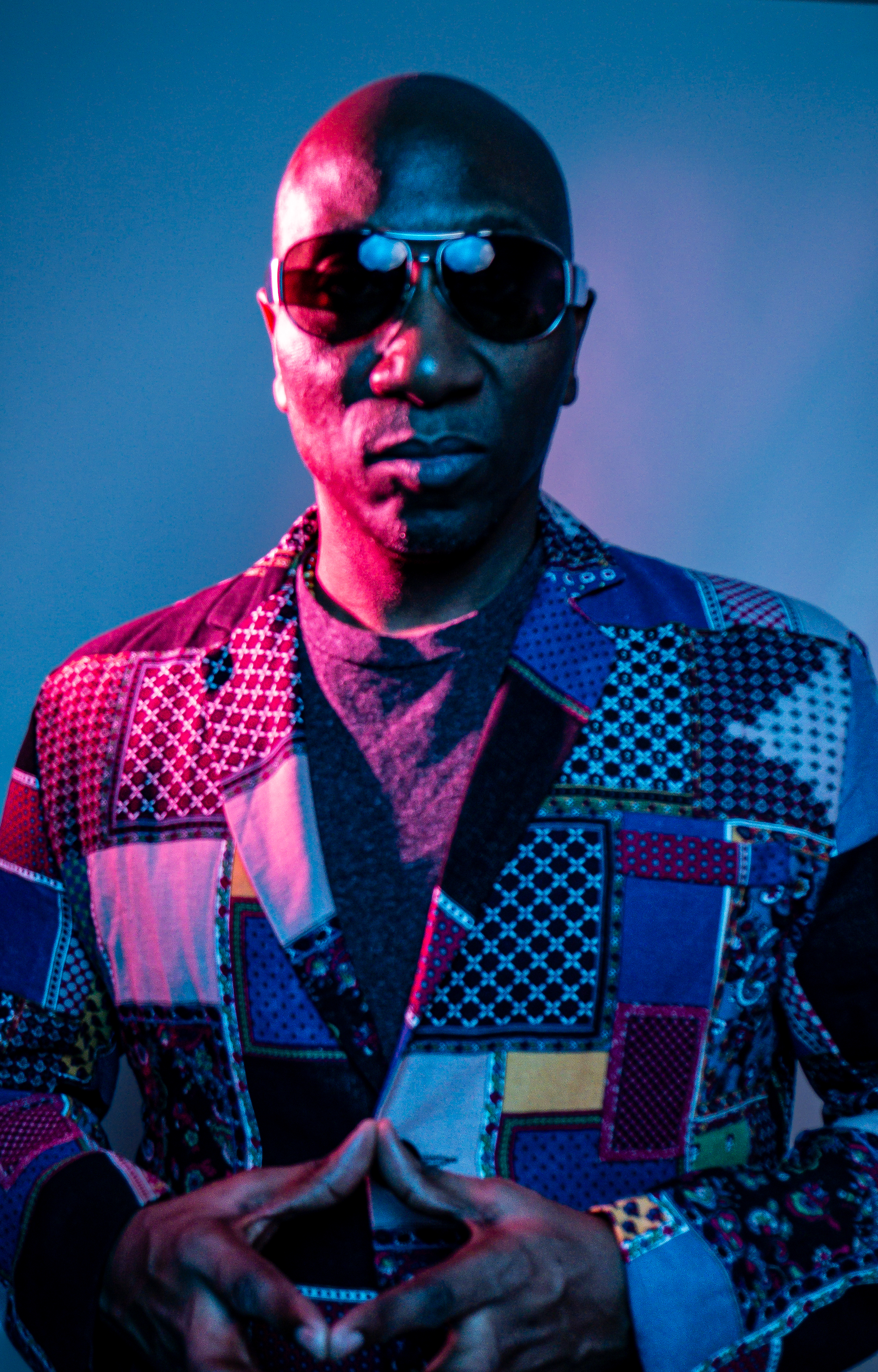 Anthony Llewellyn in sunglasses under blue and magenta lighting
